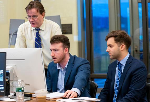 Image of students working with a faculty member in the Investment Center on campus.