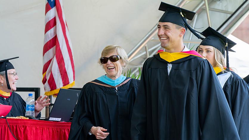Image of Deb DiCaprio in her role of prepping students on their way to the stage on Commencement Day.